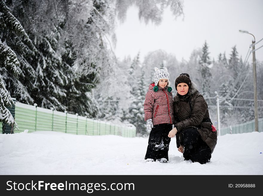 Portrait of young mother and her adorable daughter in the snow on a bright winter day. Portrait of young mother and her adorable daughter in the snow on a bright winter day