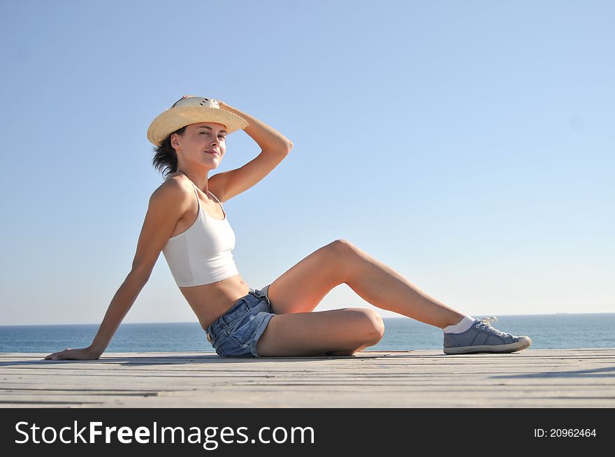 Young woman sitting on the beach in straw hat. Young woman sitting on the beach in straw hat