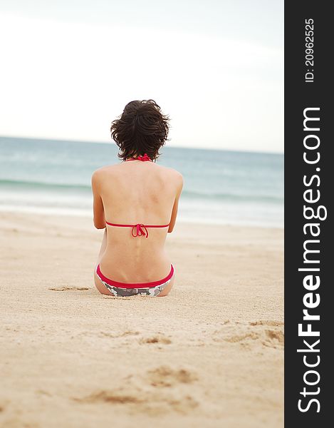 Young woman on the beach near the sea meditating