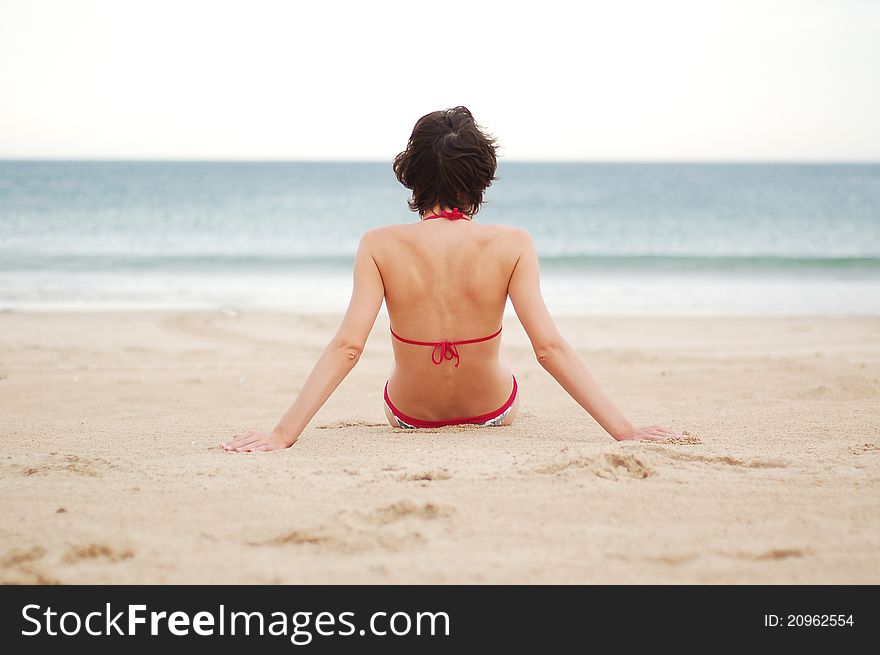 Young woman on the beach near the sea meditating