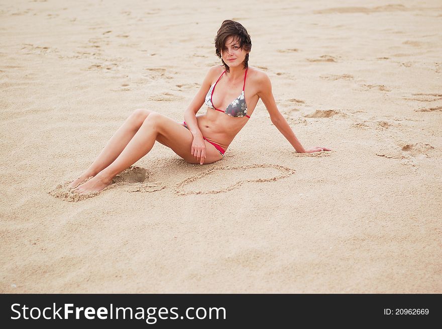 Young woman on the beach with the draw heart