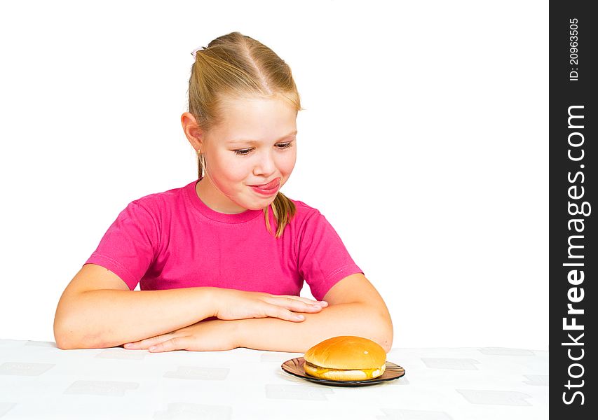 Little girl looking hamburger with tongue out on white