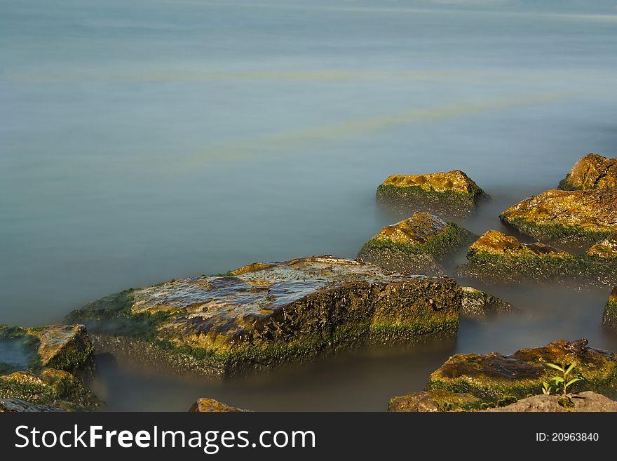 Daytime long exposure image of rocks ina lake featuring silky misty water. Daytime long exposure image of rocks ina lake featuring silky misty water