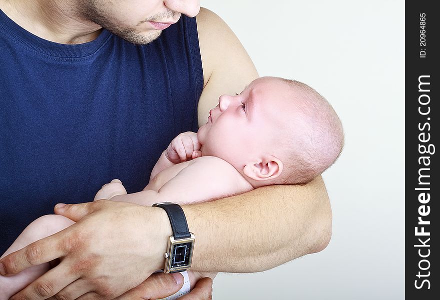 A good father holding his son in his arms and looks at it on a light background