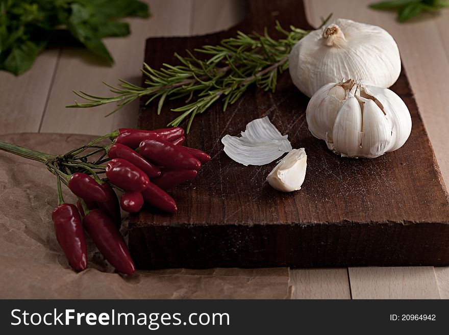 Hot pepper, garlic, rosemary on a chopping board