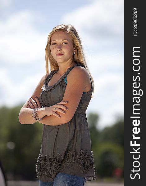 Beautiful young blond model posing outside with arms crossed