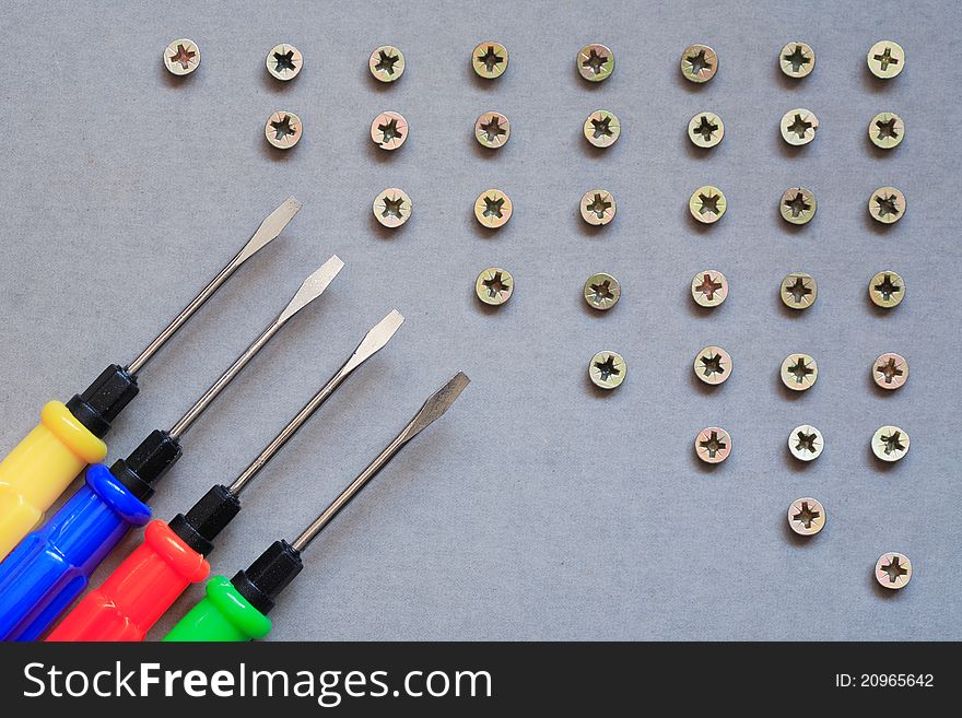 Industrial concept. Set of color screwdrivers near lot of screws. Industrial concept. Set of color screwdrivers near lot of screws