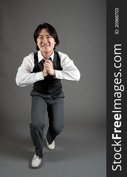 Asian male jazz dancer poses in front of studio gray backdrop.