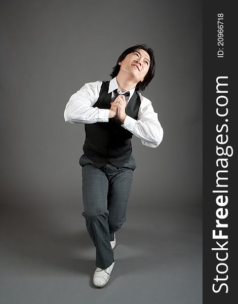 Asian male jazz dancer poses in front of studio gray backdrop.