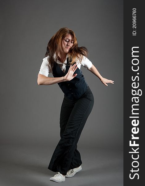 Caucasian female jazz dancer poses in front of a studio gray backdrop.