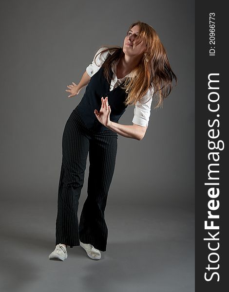 Caucasian female jazz dancer poses in front of a studio gray backdrop.