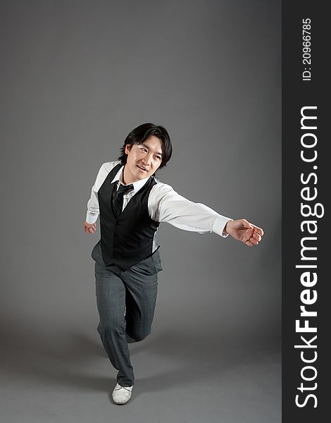 Asian male jazz dancer poses in front of studio gray backdrop.