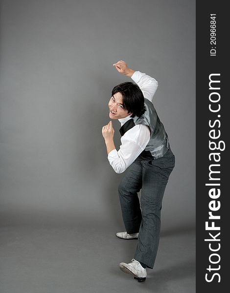 Asian male jazz dancer poses in front of studio gray backdrop.