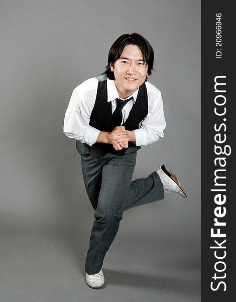 Asian male jazz dancer poses in front of studio gray backdrop.