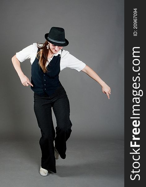 Caucasian female jazz dancer poses in front of a studio gray backdrop.