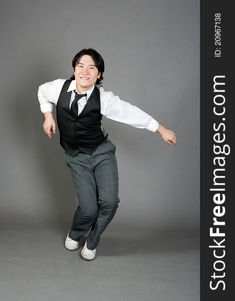 Asian male jazz dancer poses in front of studio gray backdrop.