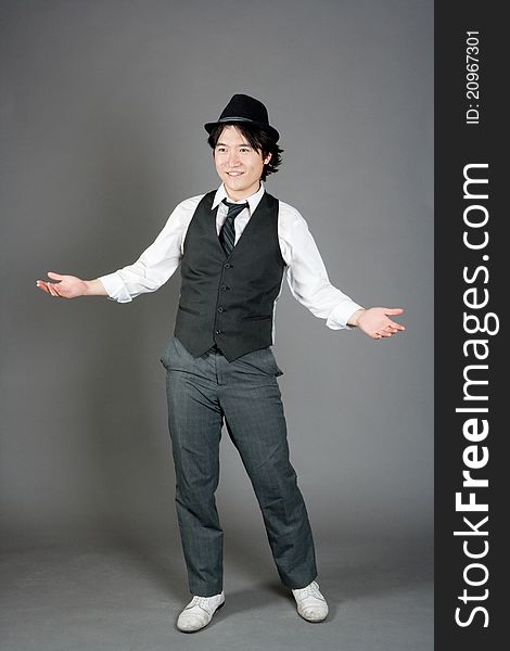 Asian male jazz dancer poses in front of studio gray backdrop.