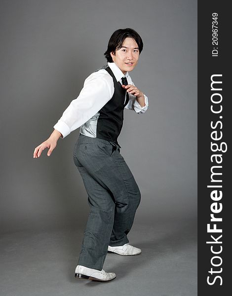 Asian male jazz dancer poses in front of studio gray backdrop.