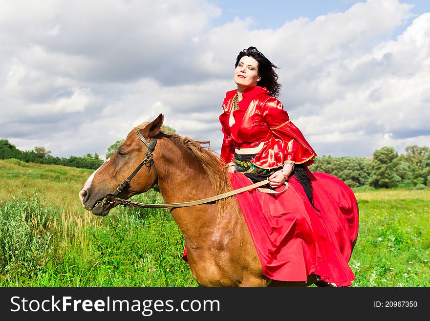 Beautiful gypsy girl riding a horse in the field