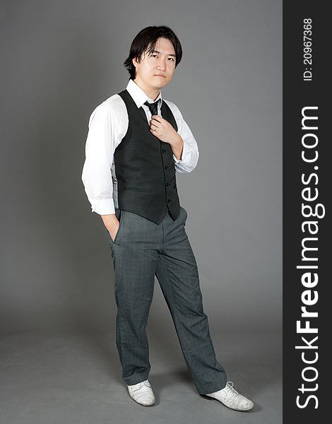 Asian male jazz dancer poses in front of studio gray backdrop.
