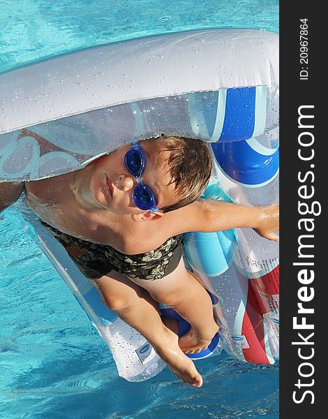 Little young boy on air matress in swimming pool