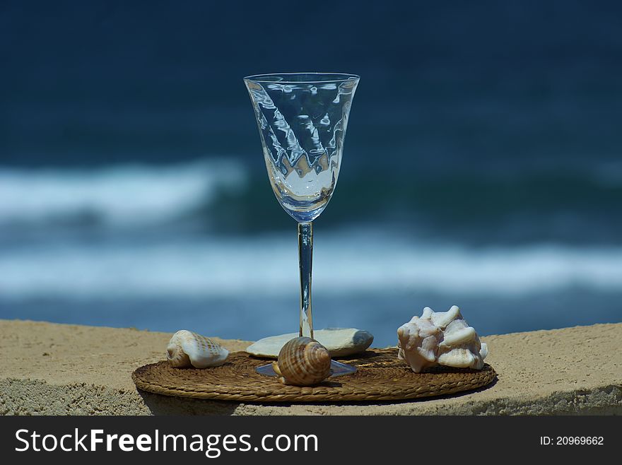 Empty wine glass with sea shells and a reflection of the sky and the sea. Empty wine glass with sea shells and a reflection of the sky and the sea