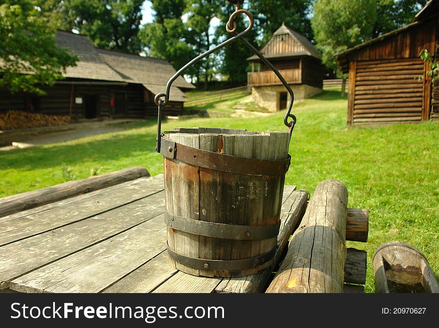 Wooden well with folk architecture in the background