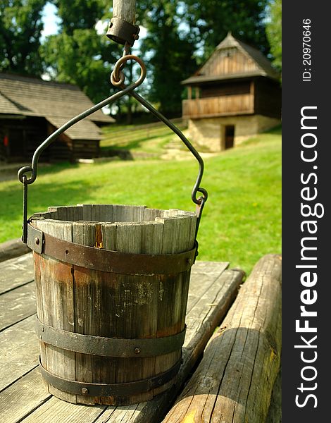 Wooden well with folk architecture in the background