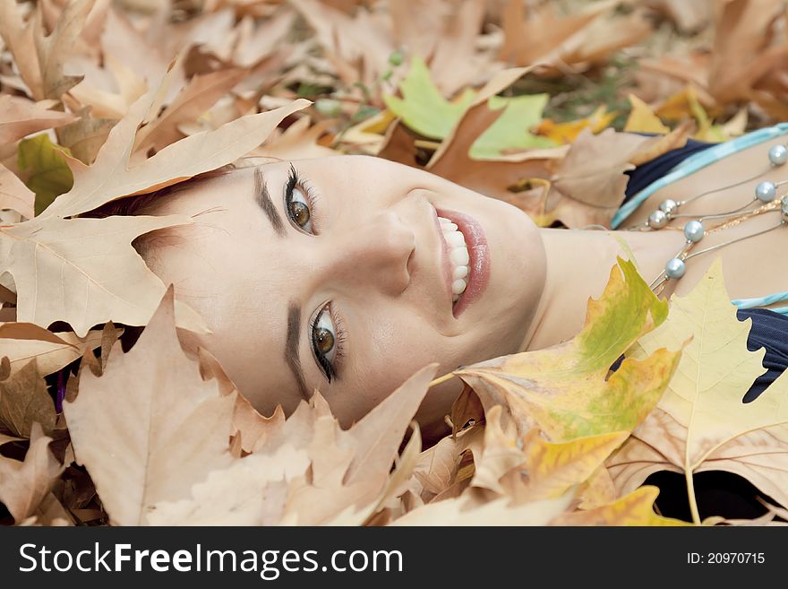 The beautiful woman lies on yellow leaves. The beautiful woman lies on yellow leaves