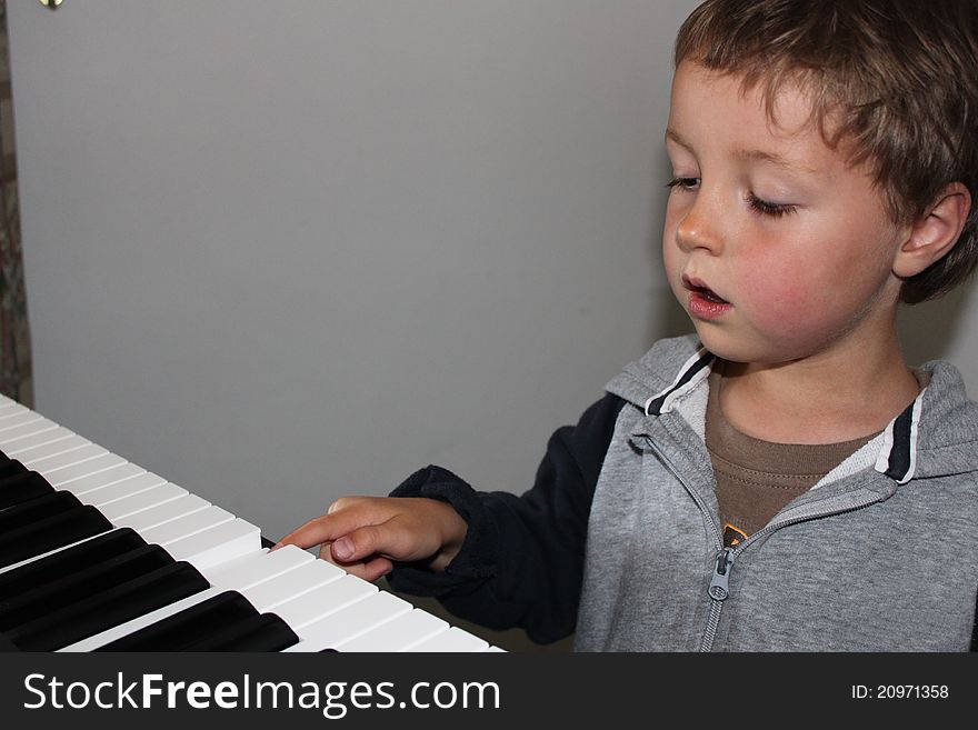 A Young Boy pressing a note on a piano keyboard. A Young Boy pressing a note on a piano keyboard