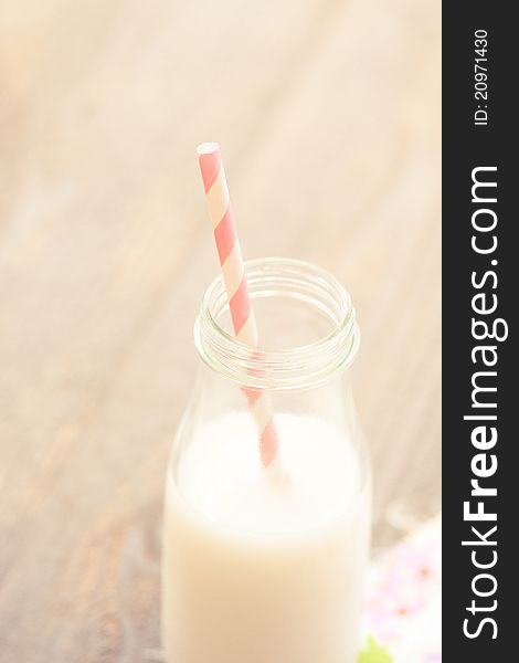 A sweet pink and white striped straw is ready for sipping farm fresh milk out of a glass bottle. A sweet pink and white striped straw is ready for sipping farm fresh milk out of a glass bottle.
