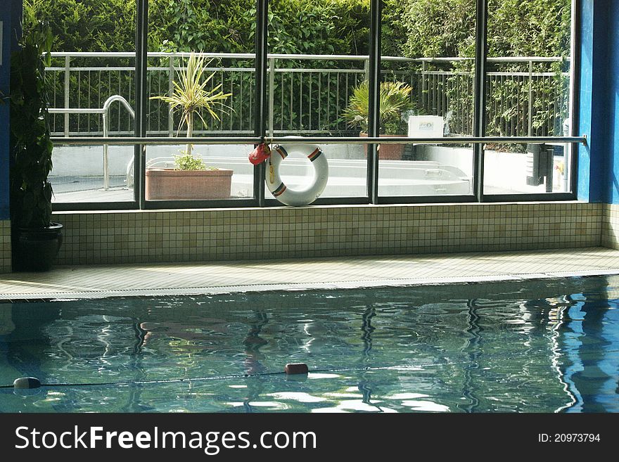 Indoor swimming pool with green plants and spa outside