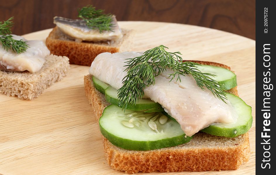 Herring on a piece of rye bread with cucumbers and dill