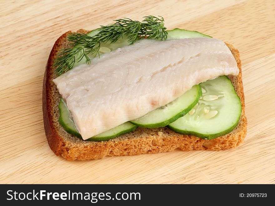 Herring on a piece of rye bread with cucumbers and dill