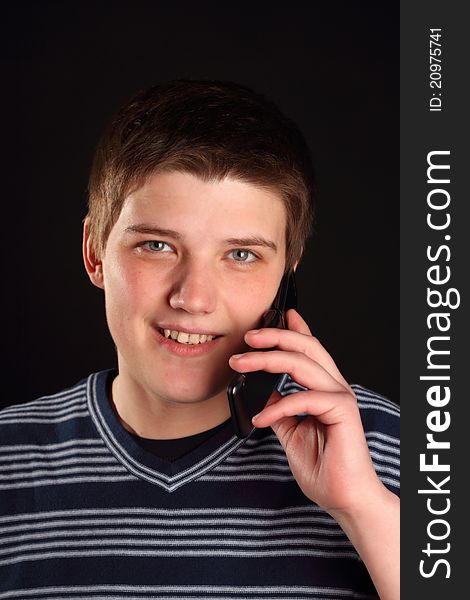 A young boy talking on the phone on a black background