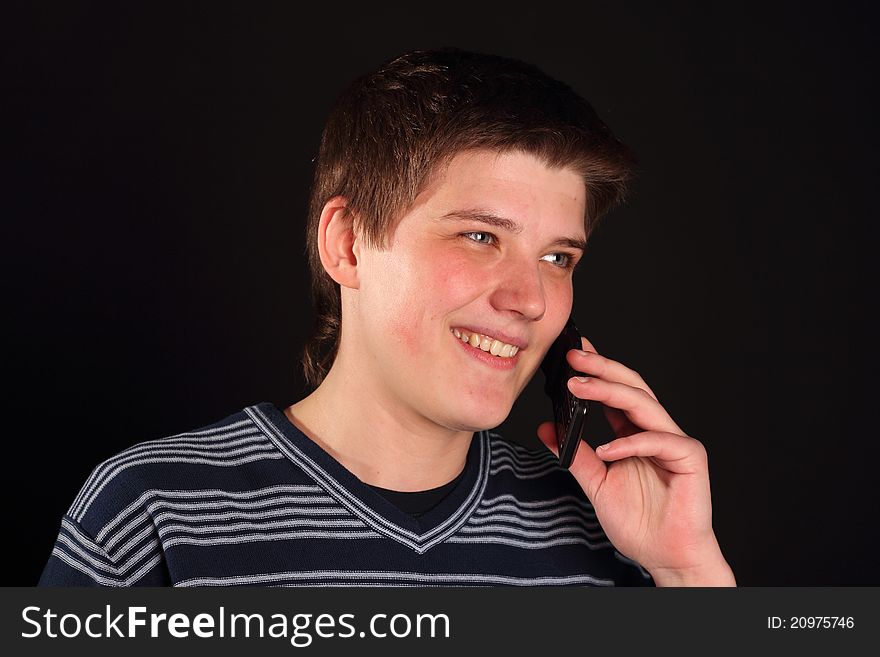 A young boy talking on the phone on a black background