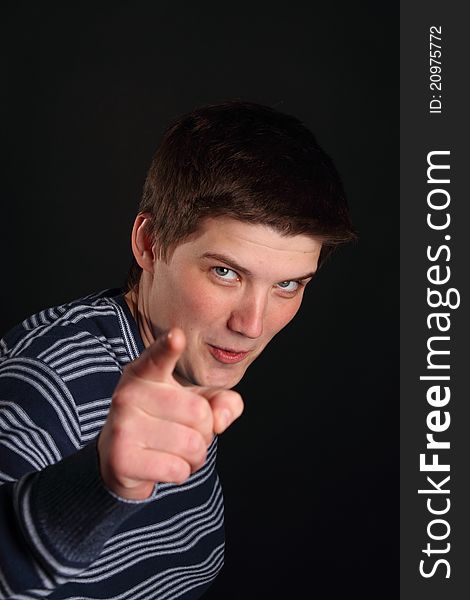 A young boy pointing with his finger on the black background