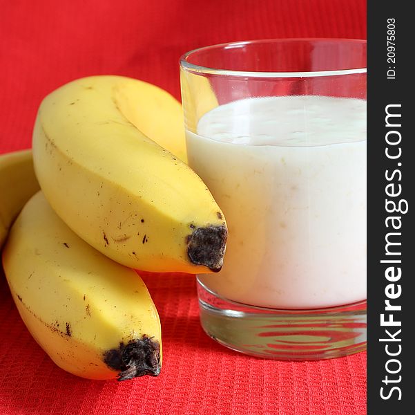 Banana smothie in a glass on the red background