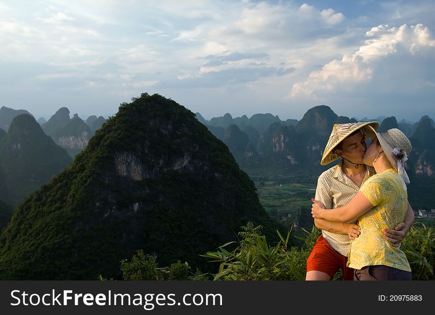 Portrait image of lovely couple kissing on top of the mountain at sunset. China