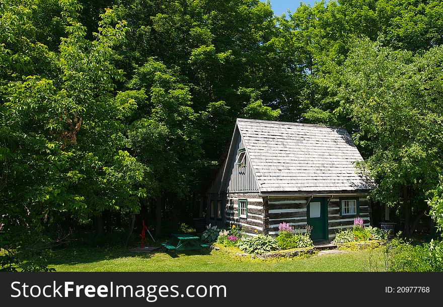 Wide angle view of a preserved pioneer log cabin nestled in the woods. Wide angle view of a preserved pioneer log cabin nestled in the woods.