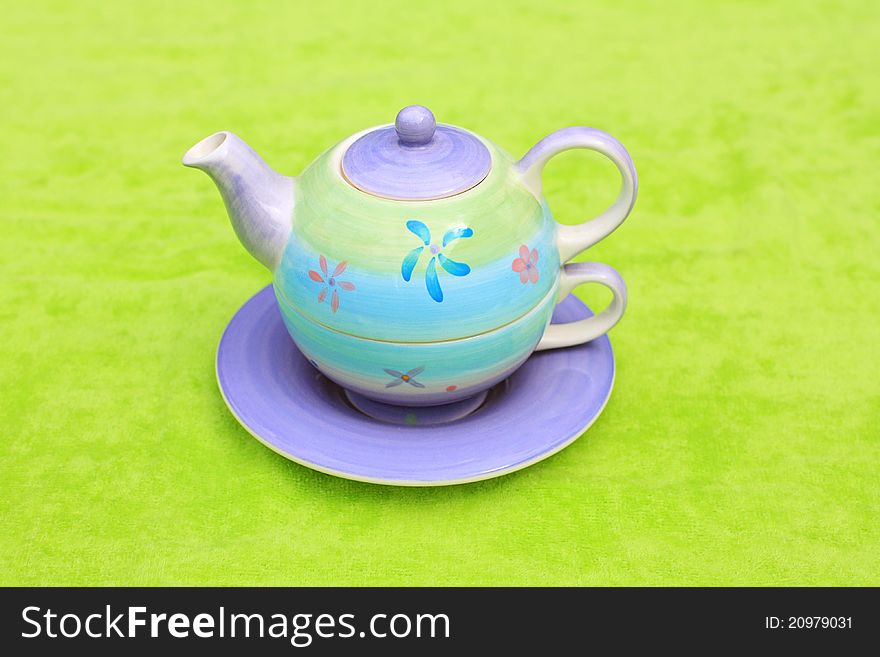Lovely pastel teapot on green background