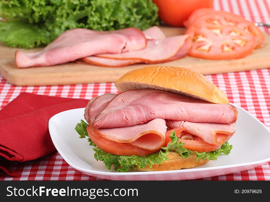 Ham, lettuce and tomato sandwich on a white plate. Ham, lettuce and tomato sandwich on a white plate