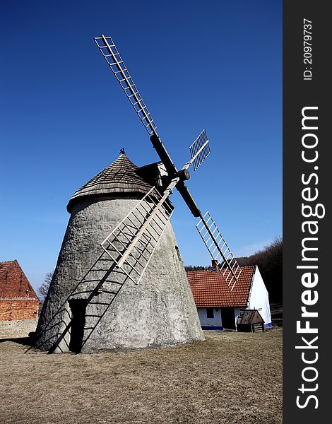 Photography of old wind mill with houses in the background