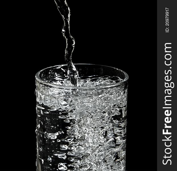 Filling water into glass and black background. Filling water into glass and black background