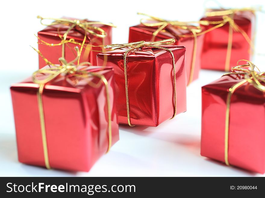 A close up image of Christmas Gifts in red with gold string bows.