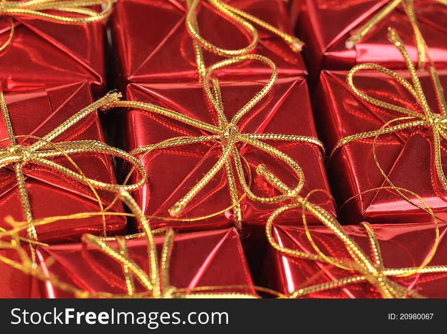 Close up image of wrapped gift boxes in red with gold string bows. Close up image of wrapped gift boxes in red with gold string bows.