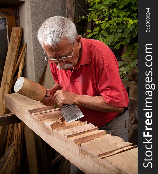Old woodcarver working with mallet and chisel 8