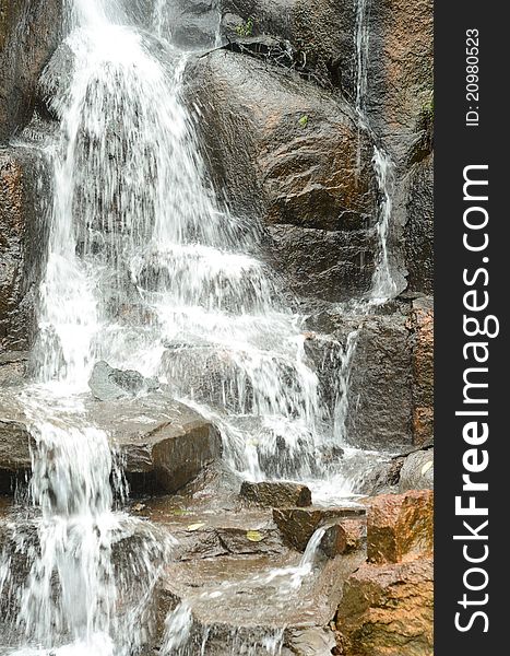 A waterfall is pouring down on stones, showing grandeur and power. A waterfall is pouring down on stones, showing grandeur and power.