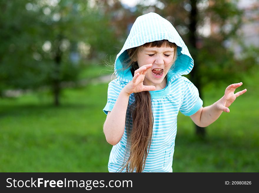 Cute child girl in blue hood poses outdoors making scary face. Cute child girl in blue hood poses outdoors making scary face