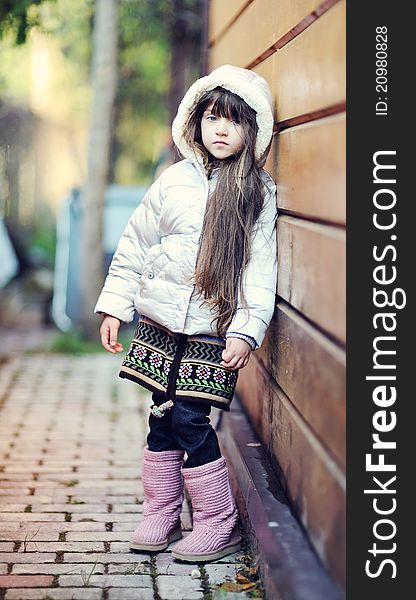 Full length outdoor portrait of adorable child girl with long dark hair in colorful warm clothe. Full length outdoor portrait of adorable child girl with long dark hair in colorful warm clothe